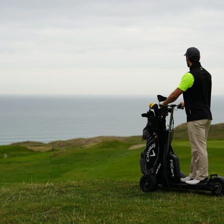 Golfer on a three wheeled scooter at the top of a fairway hill